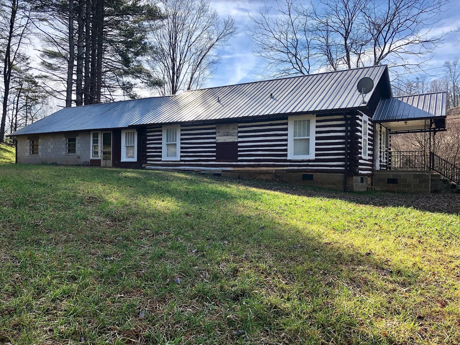 Long single-story wood-sided house on a grassy lot with trees